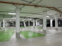 an empty parking garage with parking lights on the ceiling and green floor area on the floors