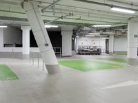 an empty parking garage with parking lights on the ceiling and green floor area on the floors