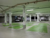 an empty parking garage with parking lights on the ceiling and green floor area on the floors