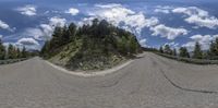 a couple of 360 - mirrors in front of the sky and hills on a road