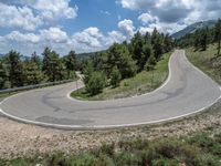 the curved road curves in a direction on an alpine slope against a blue sky with scattered clouds