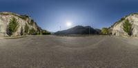 the mountains are in the background with the sun in the sky and an intersection with an empty road