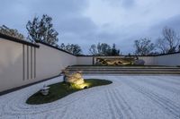 a large white stone rock garden in front of white walls and steps leading up to a fountain and sculpture