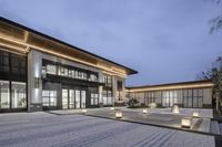 a building with lights on it sitting in the courtyard area of the building surrounded by lit grass and stone