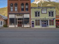 a red fire hydrant sitting in front of an old store window and building next to an open air field