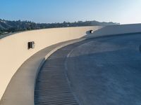 an empty white wall with a long curved walkway near it on the outside of a building