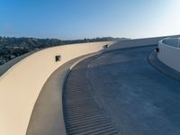 an empty white wall with a long curved walkway near it on the outside of a building