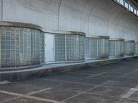 two empty parking spaces with two empty doors and a large window on the wall between two buildings