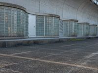 two empty parking spaces with two empty doors and a large window on the wall between two buildings