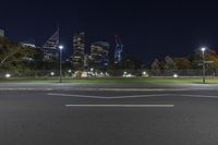 a very quiet street with skyscrapers at night as seen from across the street in the distance