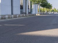 a man riding a red skateboard down a quiet street in front of a tall white building