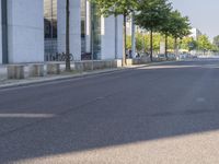 a man riding a red skateboard down a quiet street in front of a tall white building