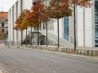 a lone street with no cars in the street and a building and stairs behind it