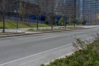 an empty street with no one on it and trees in the distance in front of some buildings