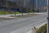 an empty street with no one on it and trees in the distance in front of some buildings