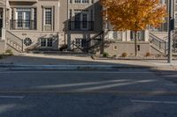 a tree and stairs line a quiet street in an autumn day, near some apartment buildings