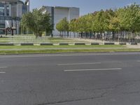 a street with grass, trees and a building behind it is one empty road with no traffic in front