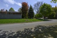 a empty street lined with homes and trees in a neighborhood setting with grassy lawn area,