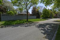 a empty street lined with homes and trees in a neighborhood setting with grassy lawn area,