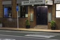 a photo of a sign for the quiet wellington hotel on a street corner with plants