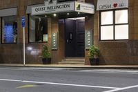 a photo of a sign for the quiet wellington hotel on a street corner with plants