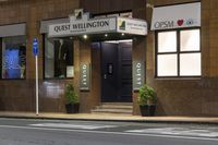 a photo of a sign for the quiet wellington hotel on a street corner with plants