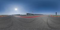 a wide angle shot of a race track with an oval pattern in the middle and cars moving in opposite directions