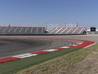 an empty track at a motorsports club with some red and white stripeing on it