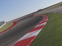 an empty track at a motorsports club with some red and white stripeing on it