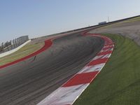 an empty track at a motorsports club with some red and white stripeing on it