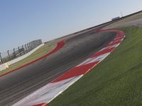 an empty track at a motorsports club with some red and white stripeing on it