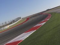 an empty track at a motorsports club with some red and white stripeing on it