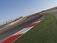 an empty track at a motorsports club with some red and white stripeing on it