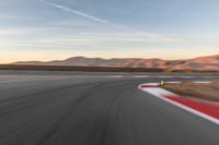 a photo of a dirt race track with sun setting in the distance of the track