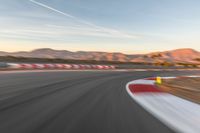 a photo of a dirt race track with sun setting in the distance of the track