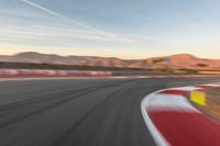 a photo of a dirt race track with sun setting in the distance of the track