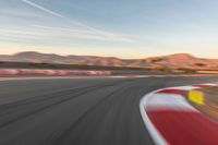 a photo of a dirt race track with sun setting in the distance of the track