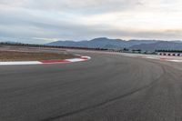 a photo of a dirt race track with sun setting in the distance of the track