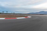 a photo of a dirt race track with sun setting in the distance of the track