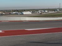 an empty track at a motorsports club with some red and white stripeing on it