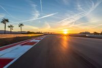 a photo of a dirt race track with sun setting in the distance of the track