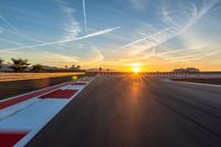 a photo of a dirt race track with sun setting in the distance of the track