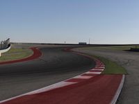 an empty track at a motorsports club with some red and white stripeing on it