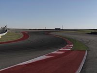 an empty track at a motorsports club with some red and white stripeing on it