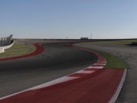 an empty track at a motorsports club with some red and white stripeing on it