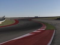 an empty track at a motorsports club with some red and white stripeing on it