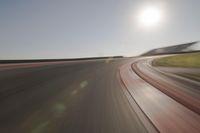 blurred shot of race track with car on one side and sun in the other side