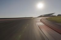 blurred shot of race track with car on one side and sun in the other side