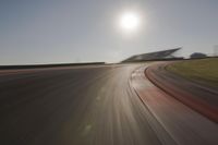 blurred shot of race track with car on one side and sun in the other side