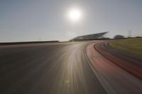 blurred shot of race track with car on one side and sun in the other side